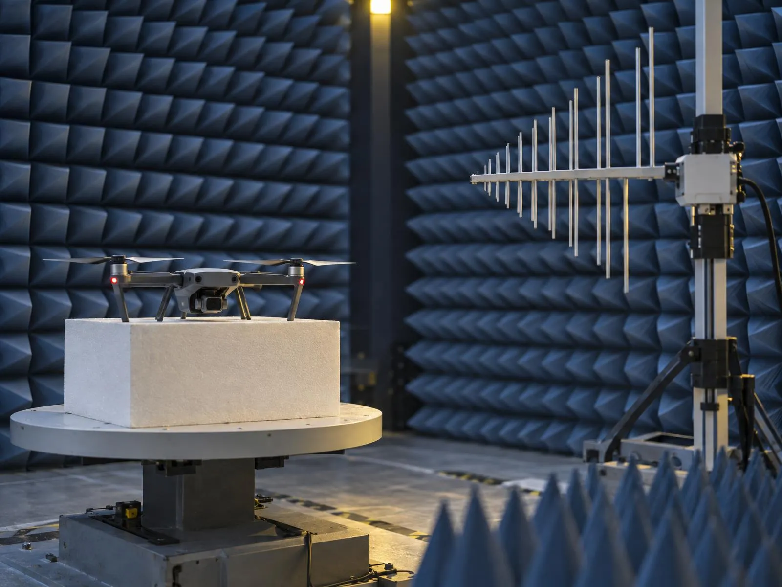 Drone posé sur une table tournante dans une chambre semi-anéchoïque, face à une antenne de mesure